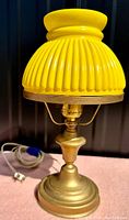 Front view of vintage brass desk lamp with yellow ribbed glass shade and cord.