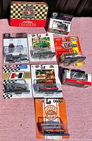 Overview of all diecast cars sealed in original packaging along with the Coca-Cola NASCAR collectible tin box with matches.