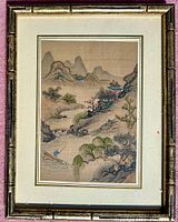 Framed Japanese watercolor artscape on silk with mountainous landscape and river scene including a fisherman in a boat and temple structure.