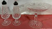 Full set of Waterford crystal compote and salt and pepper shakers shown on red surface.
