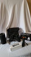 Photo showing all items in the lot including Bluetooth speaker, binoculars with case, flashlight, and boxed security light bulb.