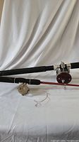 Photo showing two fishing rods laid out side by side with reels attached on a white cloth background.