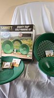 Complete kit showing gold pans, classifier sieve, bottle, paydirt bags, and booklet with the original packaging box for the Garrett Gravity Trap Gold Panning Kit.