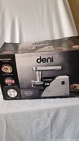 Box showing the brand Deni and image of the meat grinder model with tray and grinding unit.