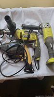 Side view of the Ryobi angle grinder and the black handheld tool with cords shown tangled