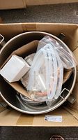 Box containing stainless steel distillation pot with silicone tubing and fittings packed inside.