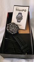 Qinux Titan PG Tactical Smartwatch in black with manual and screen protector inside the original black box.