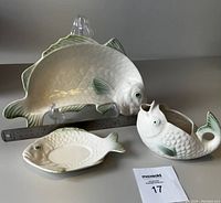 Full view of the three-piece ceramic fish serving set showing platter, sauce boat, and resting plate with ruler for scale