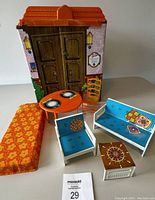 Furniture set consisting of mattress, table with plates, chair, sofa, armchair, and coffee table with colorful designs.