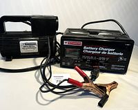 Both Motomaster battery charger and air compressor in one frame showing cables and clamps.