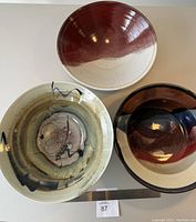 Three pottery bowls displayed together showing variety of glaze colors and form.