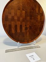 Top view showing circular teak wood serving dish with butcher block end grain pattern and dark wood tones.