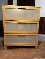 Front view of the Ikea Brimnes chest showing all three drawers with frosted panels and wooden handles