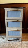 Front view showing three drawers with ribbed fronts and wooden handles.