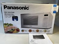 Box of the Panasonic Genius NN-SG676W microwave showing brand, model, capacity (1.3 cu ft), power (1100W), and program features.