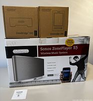Three Sonos-branded boxes: ZoneBridge 100, Controller 200, and ZonePlayer S5 Wireless Music System