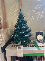 Front view of the 16 inch ceramic Christmas tree with plastic bulbs on a white shelf, showing colorful bulbs and glossy green glaze.