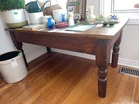 Side view showing wood coffee table with turned legs and plank top in natural light on hardwood floor