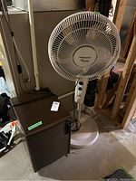 Kenmore manual control dehumidifier and Black & Decker oscillating fan together in basement.