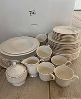 Full set of Mikasa fine china dinnerware including stacked plates of various sizes, cups, creamer, sugar bowl with lid, single salad bowl, and serving plate shown from the front.
