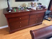 Full view of cherry-finish dresser with six drawers topped with various items