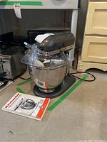 Mixer assembled with bowl and splash guard, manual on floor