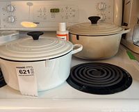 Both Dutch ovens and cleaner on stovetop, side by side