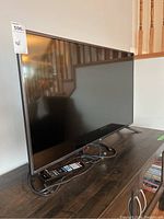 Side angle view of LG 42-inch television on stand with remote and cables on table.