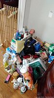 Photo of miscellaneous personal care products, storage units, shoe rack and accessories placed on floor near wall