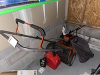 Overview of mower with grass catcher and jerry can in garage corner