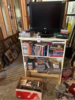 Full lot arrangement showing TV on wooden bookcase with various media and players