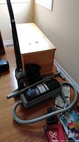 Full view of the vacuums and accessories on floor near wooden chest