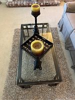 Full view of the glass top coffee table with the rug underneath and decorative items on top, showing the candle holders, candles, and tray.