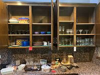 Wooden kitchen cabinets with glassware, dishes, and countertop appliances and containers