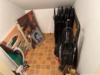 Contents of closet including foldable chairs, vacuum, framed paintings, and other items.