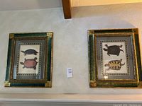 Two framed art prints hung on a wall side by side, each depicting two turtles with a decorative green and gold frame.