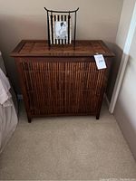 Front view of Pier 1 bamboo hamper with vertical bamboo slats and flat top lid.