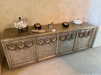 Front view of distressed metallic sideboard with decorative items on top