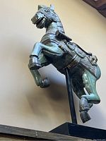 Side view of the wooden horse showing the carved and painted details, rearing pose, and mounted base