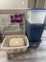 Photo showing stacked blue Rubbermaid bins, white laundry basket, white metal step shoe rack, and Swiffer Wet Jet refill boxes on top of the shoe rack.