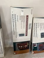 Boxed Sauder Model 2750 audio/video storage cabinet with product details and dimensions shown on packaging.