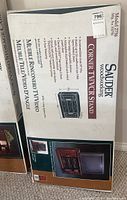 Box of Sauder Woodworking Corner TV/VCR Stand Model 2756 showing front with brand and product info