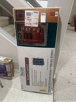 Photo of original boxed Sauder Woodworking Audio Cabinet packaging, showing product image and details.