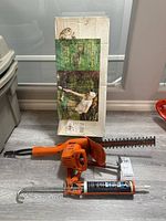 Black and Decker electric hedge trimmer with safety guard, displayed with its original box in the background