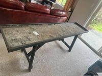 Long wood framed plant table with a metal liner surface, shown from distance to display full size and structure on wood crossed legs.