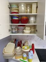Four shelves of assorted Tupperware and Rubbermaid plastic storage containers with lids in different sizes and colors including vintage pieces.