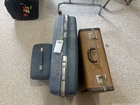 Photo showing three pieces of luggage; large blue Samsonite suitcase in the middle, small blue soft case on the left and a brown vintage suitcase on the right.