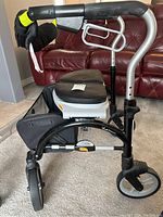 Side view of black and silver Evolution walker showing padded seat, handle, and storage pouch.