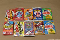 Top view of 10 different sealed baseball card retail packs from the late 80s and early 90s showing various designs and colors