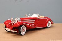 Front and side angled view of red 1936 Mercedes 500 K model with whitewall tires and beige interior.